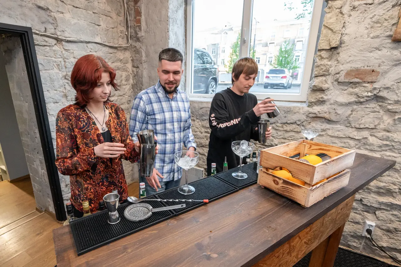 Three participants at the counter with a crate of citrus in front